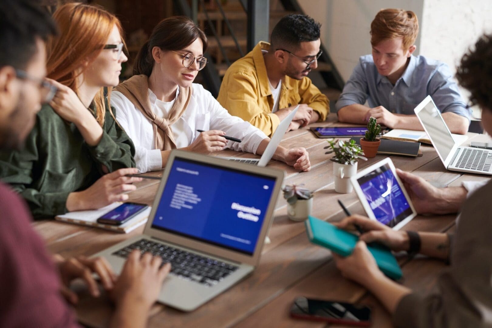 pexels-fauxels-3184325 A group of people sitting around a table with laptops.